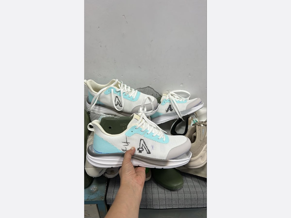Trial shoes in white and pale blue with the logo position drawn on by hand in marker, next to green lasts